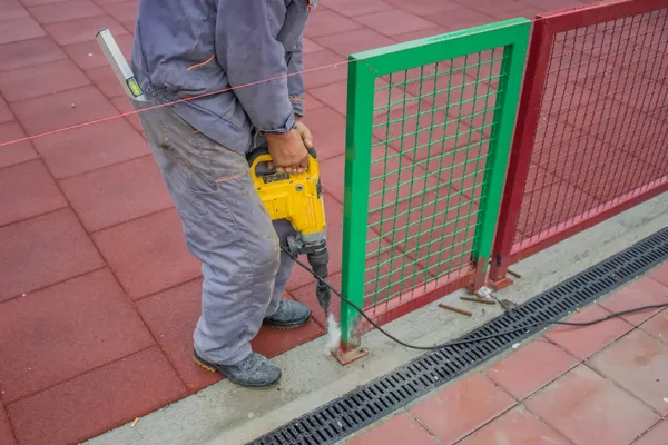 Trabalhador da construção usa uma broca para fazer furos em um concreto — Fotografia de Stock