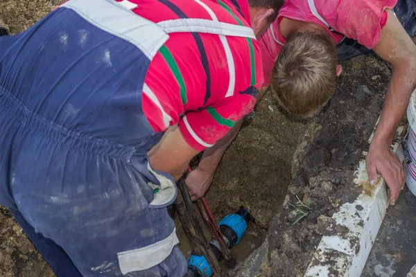 Los trabajadores de servicios públicos sostiene la llave inglesa y en la reparación de trincheras el pip roto — Foto de Stock