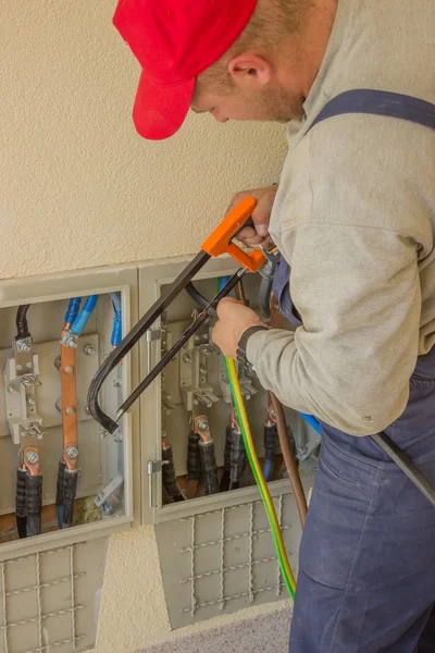 Electrician working with a chainsaw in the electrical cabinet — Stock Photo, Image
