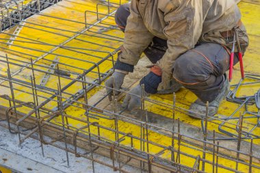 Builder worker gearing up steel rods for a concrete clipart