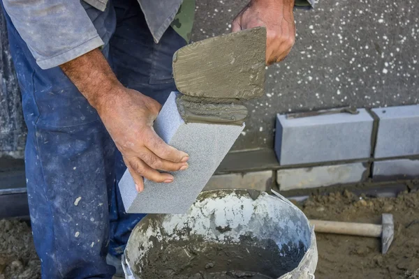 Construtor segurando um tijolo e com alvenaria espátula espalhando e sh — Fotografia de Stock