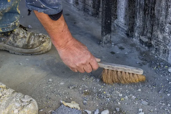 Travailleur de la construction avec balai balayant béton — Photo