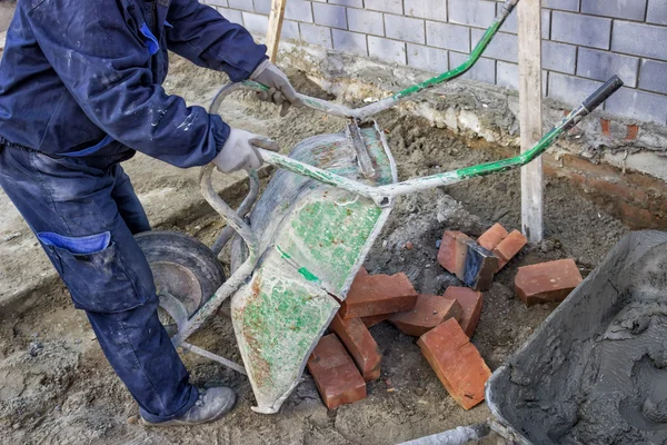 Arbeiter laden Schubkarre mit Ziegelsteinen ab — Stockfoto