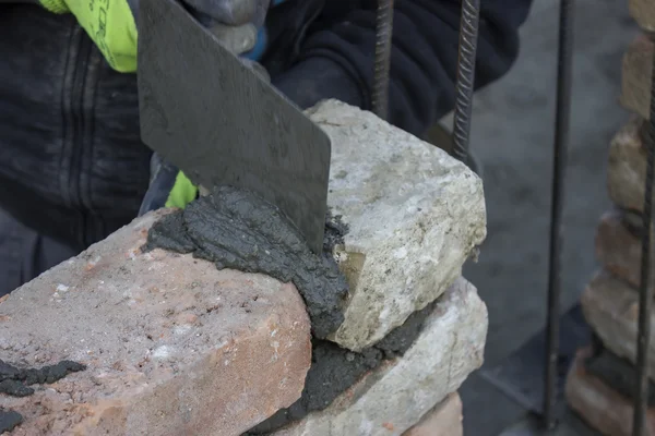 Brick mason using trowel to spread a mortar — Stock Photo, Image