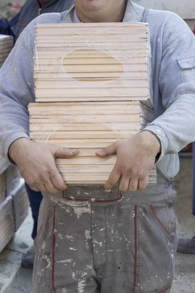 Worker carries packages of beech wood profiles 2 — Stock Photo, Image