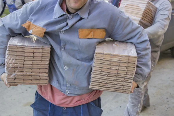Arbeiter trägt Pakete mit Buchenholzprofilen — Stockfoto