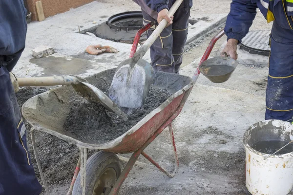 Arbetstagare blanda cement för hand i skottkärra — Stockfoto