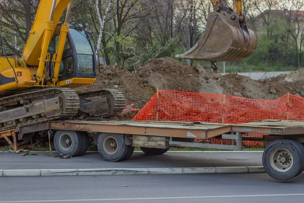 Låg säng lastbil transporterar grävmaskin — Stockfoto