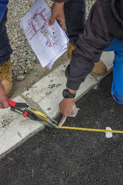 Road paint workers with measuring tape — Stock Photo, Image