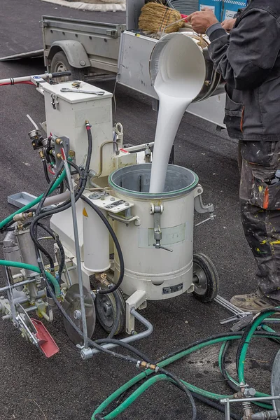 Road worker filling paint machine with paint — Stock Photo, Image