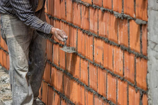 Trabalhador construtor, parede bloco de argila e espátula — Fotografia de Stock