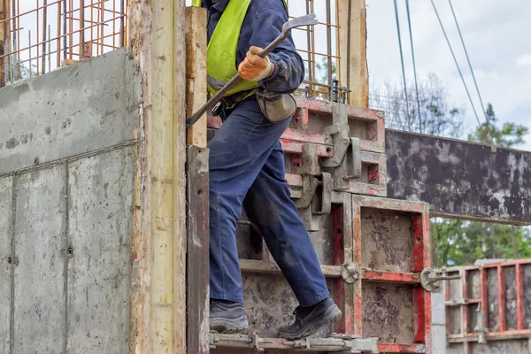 Construtor trabalhador remoção de elementos de cofragem com pé de cabra — Fotografia de Stock