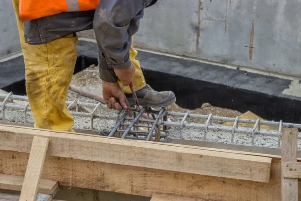 Travailleur du constructeur attachant une entretoise à une barre d'armature — Photo