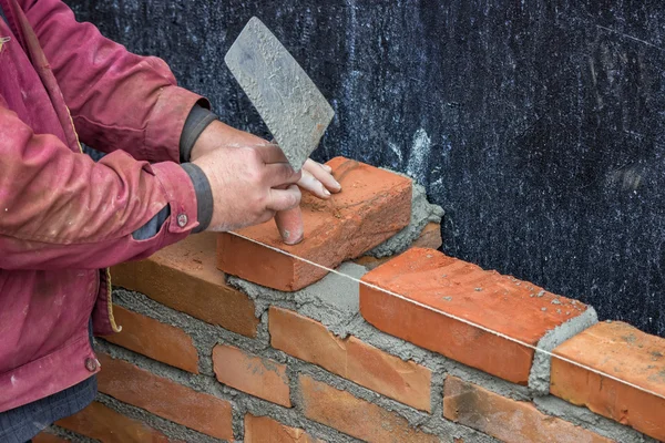 Ouvrier constructeur avec truelle pose de briques d'argile solide — Photo