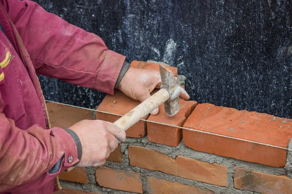 Ouvrier constructeur avec marteau maçon pose de briques d'argile solide — Photo