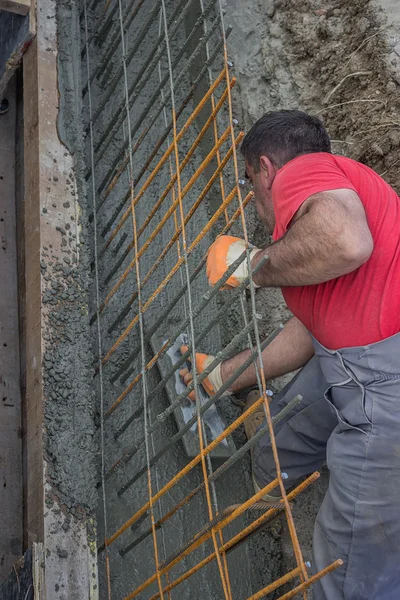 Stavební dělník hladké čerstvý beton s lopatkou v příkopu — Stock fotografie