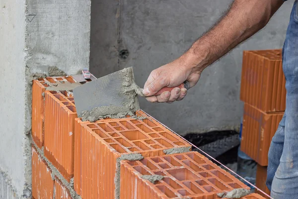 Travailleur de la construction utilisant une truelle sur un mur de bloc d'argile creux 2 — Photo