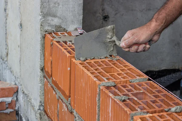 Travailleur de la construction utilisant une truelle sur un mur de blocs d'argile creux — Photo