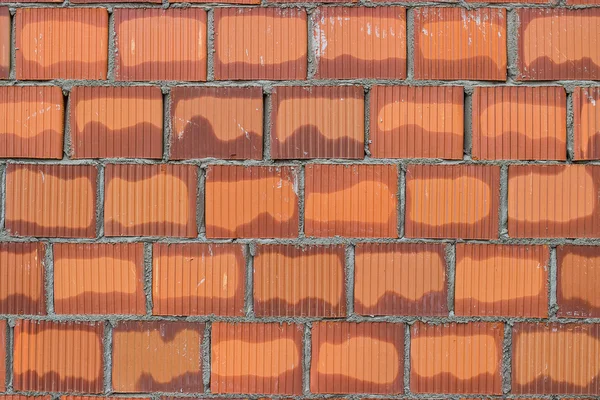 Bloque de arcilla hueca naranja en mortero fresco, fondo de pared —  Fotos de Stock