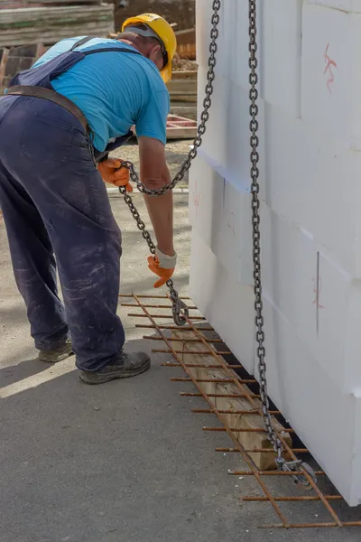 Pracovník na platformě s bílou polystyren shee montáž háků jeřábů — Stock fotografie