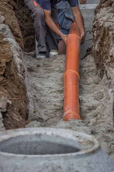 Trabajadores colocando tubos de PVC en el fondo de la zanja 2 — Foto de Stock