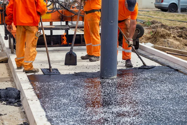 道路建設労働者は 表面を終了するためにトロウルツールを使用して 熱いアスファルトをレベリング — ストック写真