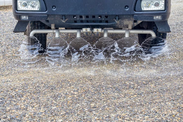 卡车在新的公路工地喷水 水车喷涂新沙石路并准备铺沥青 — 图库照片