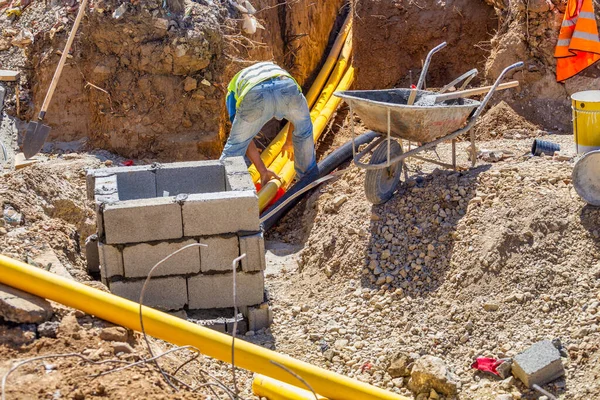 Arbeiter Die Graben Arbeiten Installieren Unterirdische Kommunikation Für Neue Gebäude Stockbild