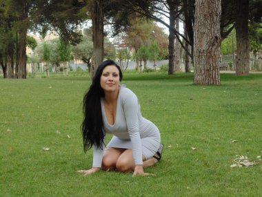 çok güzel bir kadın oturmuş çimenlerin üzerinde.