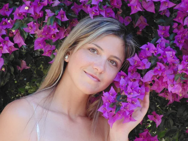 Schöne junge Frau in der Nähe der violetten Blumen. — Stockfoto