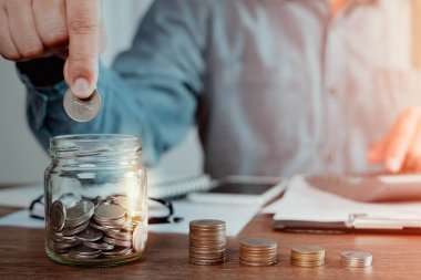 Para destesiyle cam şişe bankasına bozuk para koyarken çekilen fotoğraf büyümeyi hızlandırdı. Planlama aşaması, gelecek için para biriktirme, emeklilik fonu. Yatırım-finans hesapları kavramı.