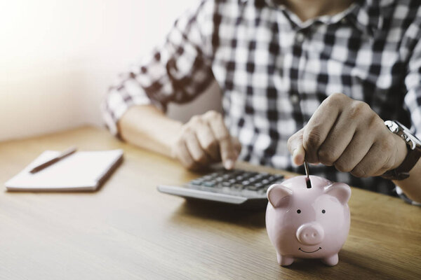 image of man hand putting coins in pink piggy bank for account save money. Planning step up, saving money for future plan, retirement fund. Business investment-finance accounting concept.