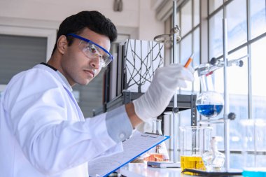 Laboratuvarda kimyasal araştırma yapan genç bilim adamları ya da araştırmacılar. Bilim adamları yeni bir ilaç ya da aşı keşfetti.