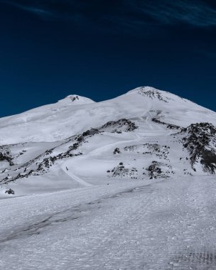 Kafkasya 'nın inanılmaz karlı dağ manzarası, açık mavi gökyüzünde Elbrus Dağı' nın zirveleri.