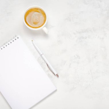 Bir fincan kahve, açık bir defter ve arka planda bir kalem. İş yeri üst görünümü