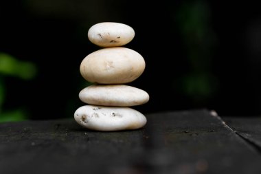 Mini Taş Yığılıyor ve Dengeleniyor Tahta tepeciklerin üzerinde Karanlık Arkaplan.