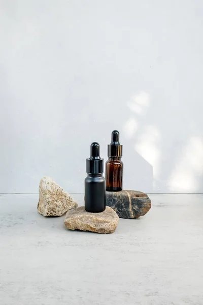 Glass dropper bottles with pipette on the stone. Cosmetic oil bottle mockup. Mockup scene. Product presentation concept.