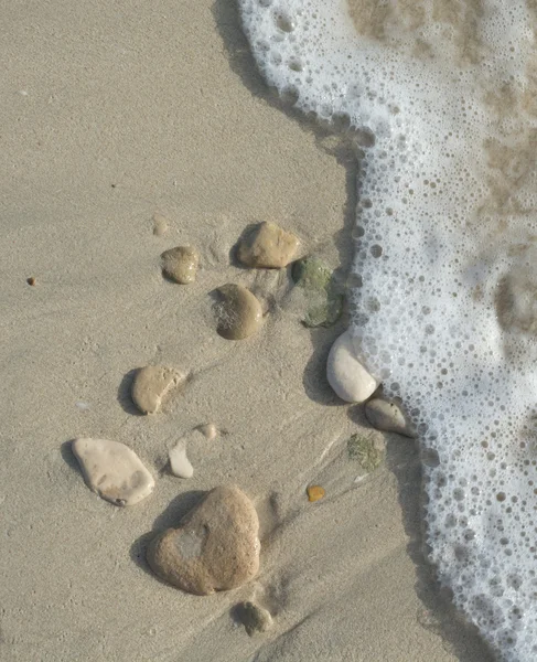 Stenar på sand och rörelse suddig våg — Stockfoto