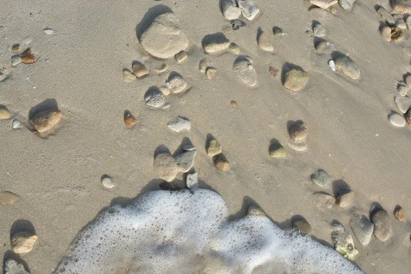Playa de arena con guijarros y pequeña ola borrosa —  Fotos de Stock