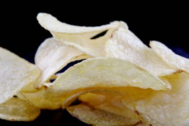Siyah arka planda lezzetli çıtır patates cipsi..