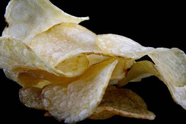 Siyah arka planda lezzetli çıtır patates cipsi..