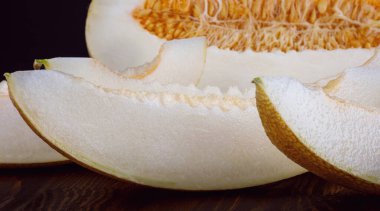 Half and pieces of ripe melon on a black background.