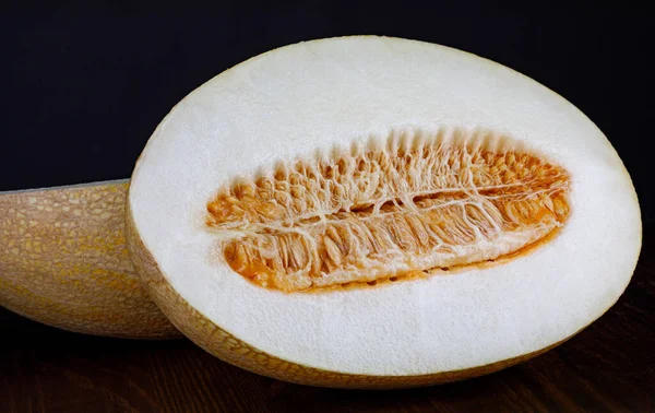 Cut ripe melon with seeds on a black background.