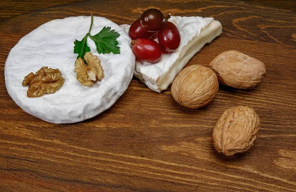 Circle Camembert Cheese Lies Wooden Board Piece Cheese Walnuts Grapes — Foto de Stock