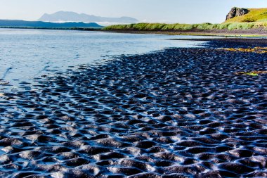 Kuzey İzlanda 'daki Vatnsnes yarımadasında ayak izleri ve çakıl taşları olan siyah sahil.