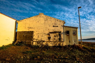 Kuzey İzlanda 'daki Hrutafiordur fiyordunda şafak vakti Bordeyri' de sarı duvarlı teneke çatılı eski terk edilmiş balık işleme fabrikası.