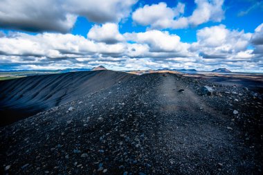 İzlanda 'nın Nordurping belediyesinde Husavik yakınlarındaki Mivatn Gölü' nde bulutlu mavi gökyüzü olan kumda lav kayaları var.