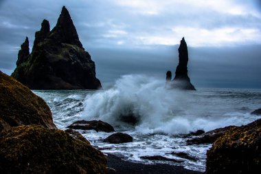 Siyah lav çakıl taşı plajı. Dalgalar, İzlanda, Vik 'teki Reynisdrangar' daki siyah lav kayalıklarına çarpıyor.