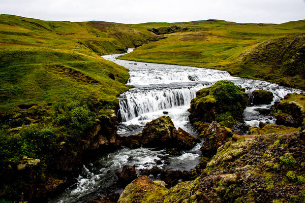 the Skogafoss waterfalls in summer with the green of the mountains and the pouring water near Vik in Iceland