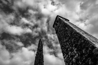 İtalya 'nın Poleo Vicenza bölgesindeki selvi ağacıyla mavi gökyüzüne karşı duran taştan çan kulesi olan küçük bir köy kilisesi.